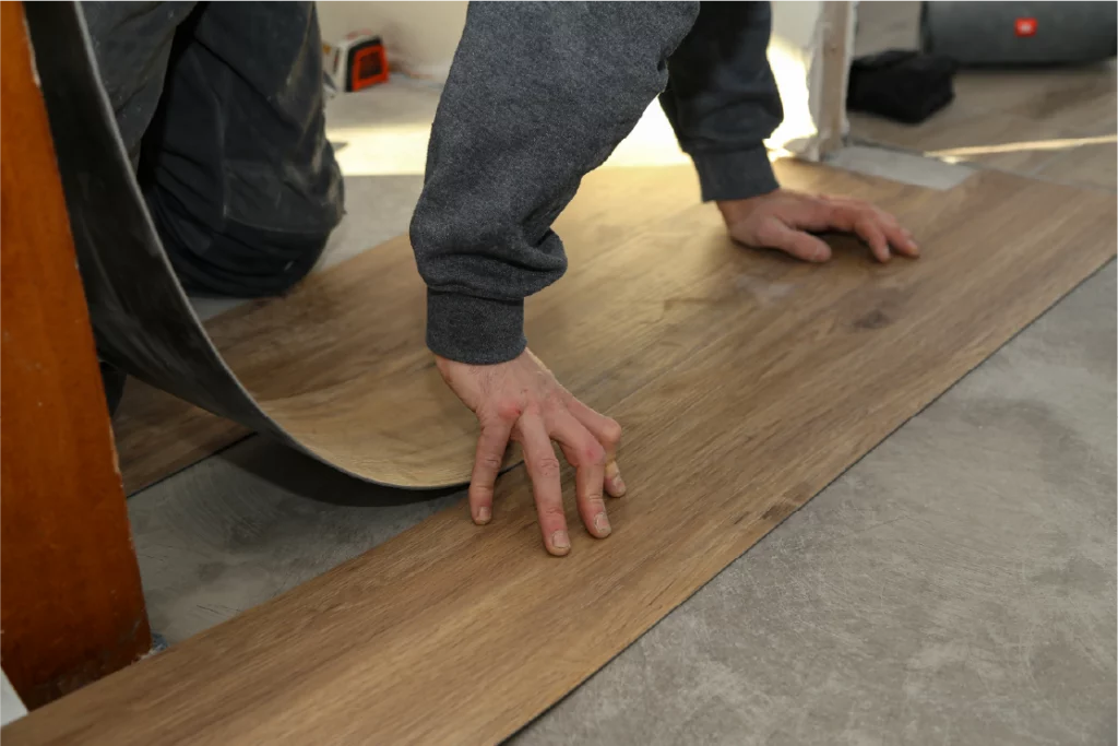 Flexibele PVC plak vloer met houtlook aandrukken op ondervloer